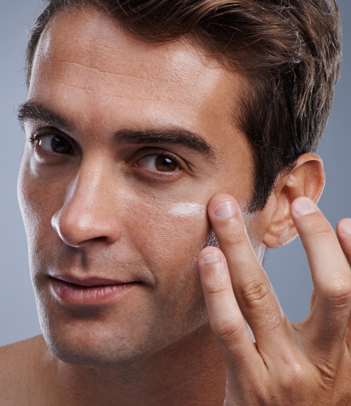 Nahaufnahme Auftragen von Gesichtscreme auf Männergesicht symbolisiert die richtige Hautpflege bei Rosacea-Behandlung